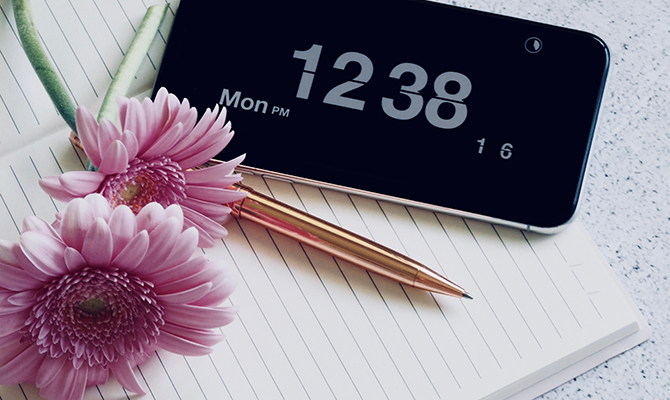 Phone showing time and pink daisy flowers